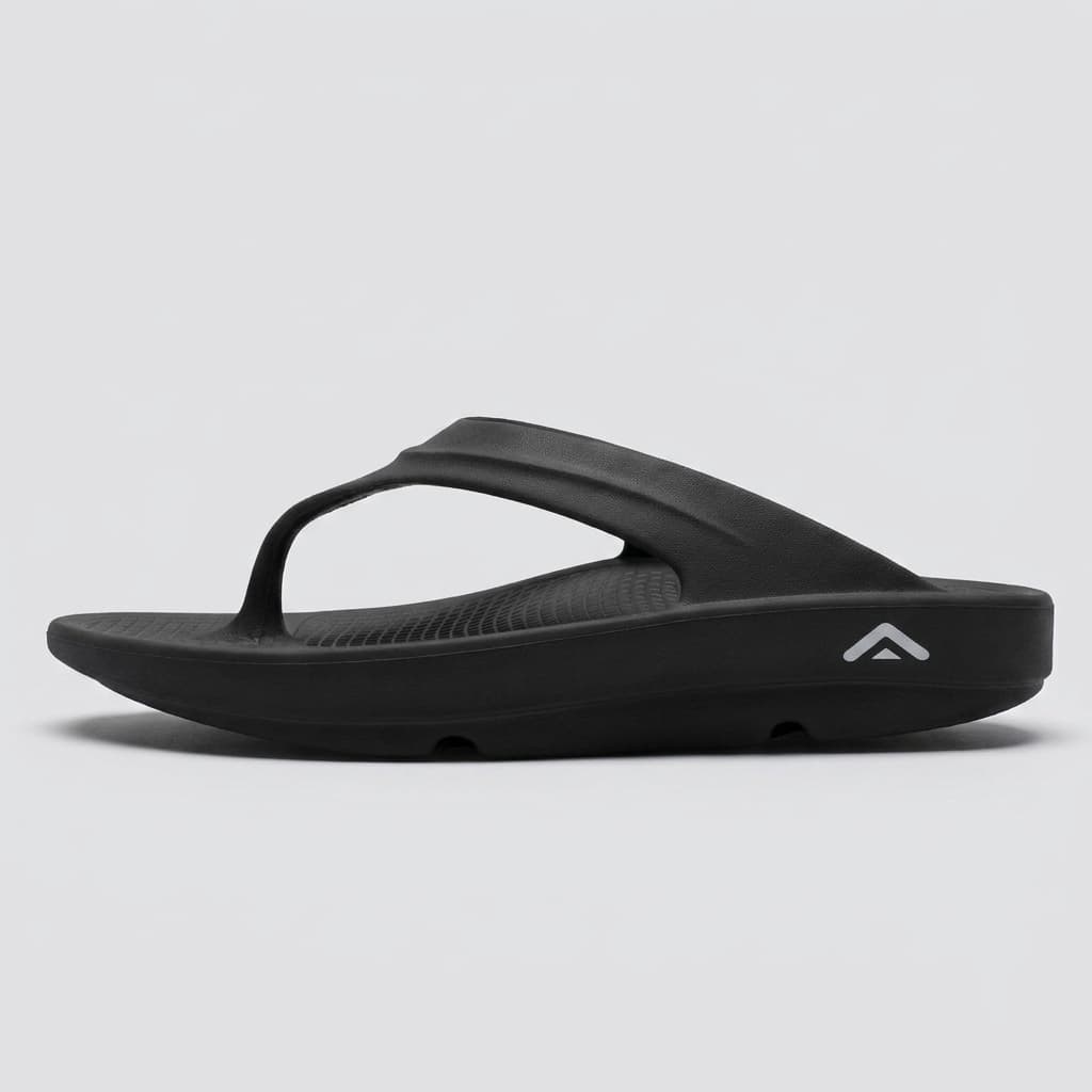 A black Fanture recovery flip flop in side profile against pale grey, showing the full thickness of the sole and its heel-to-toe rocker